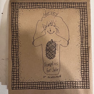 May include: A brown paper package with a hand-drawn scarecrow illustration. The scarecrow has a pumpkin body and the text "Pumpkins for Sale" and "5" scarecrow". The package is framed with a black dotted border.