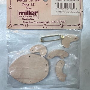 May include: A wooden Humpty Dumpty pin kit from Miller Woodcrafts. The kit includes a large oval body, head, arms, and a pin back. The packaging reads "Puttin' On The Pinz #2" and "Made in USA".
