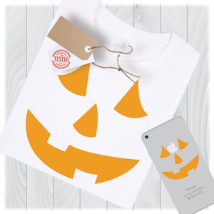 K&ouml;nnte beinhalten: Ein wei&szlig;es T-Shirt mit einem orangefarbenen K&uuml;rbisgesichtsdesign. Das Design befindet sich auch auf einer wei&szlig;en iPhone-H&uuml;lle.