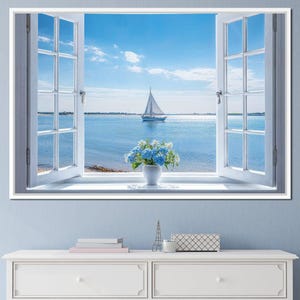 May include: A framed print depicting an open window with a view of a calm sea. A sailboat sails on the blue water under a clear sky. A white vase with blue flowers sits on the windowsill. The window frame is white.
