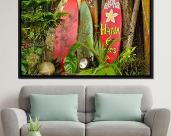 May include: Four vintage surfboards leaning against a tree trunk. The surfboards are painted in red, green, and blue with white and yellow lettering. The lettering on the front surfboard reads "Aloha Hana 6 Miles".