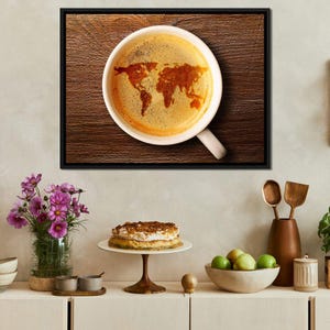 May include: A close-up of a white coffee mug with a brown wooden background. The coffee in the mug has a world map design in the foam.