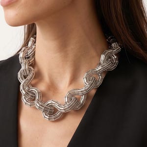 Opvallende statementketting met grove zilveren schakels, oversized ketting met in elkaar grijpende schakels, gedurfde metallic choker, moderne avant-garde damessieraden