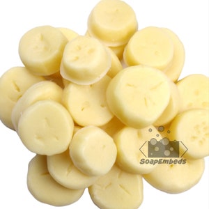 May include: A close-up of a pile of round, white, scented soap melts. The melts are smooth and have a slightly textured surface. The melts are arranged in a random pattern. The text "SoapEmbeds" is visible in the lower right corner of the image.
