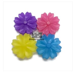 May include: Four flower-shaped silicone molds in purple, pink, yellow, and blue. The molds are designed for making soap or other crafts.