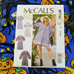 May include: A sewing pattern for a dress with a V-neck, long sleeves, and a gathered skirt. The pattern includes five different views of the dress, each with a different style of sleeve and neckline. The pattern is for sizes Lrg-Xlg and is from McCall's.