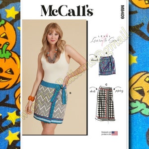 May include: A sewing pattern for a skirt with three different styles. The pattern is from McCall's and is labeled "Learn to Sew". The skirt styles include a wrap skirt with a chevron pattern, a skirt with bands, and a skirt with darts and piping.