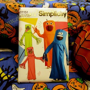 May include: Simplicity sewing pattern R11151 for making Halloween costumes. The pattern includes instructions for making three different costumes: a green monster, an orange monster, and a blue monster. The pattern is for sizes XS-XL.