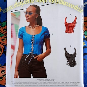 May include: McCall's sewing pattern M8182 featuring a blue corset top with lace-up detail. The pattern includes multiple view options. The image also shows a woman wearing the corset top. The text reads #MonicaMcCalls.