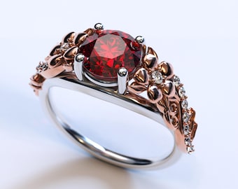 May include: A silver and rose gold ring with a large red gemstone surrounded by smaller diamonds. The ring features a floral design with delicate details.