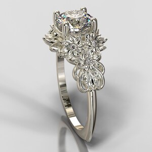 May include: A silver ring with a large, clear, round gemstone surrounded by smaller gemstones and intricate floral designs.