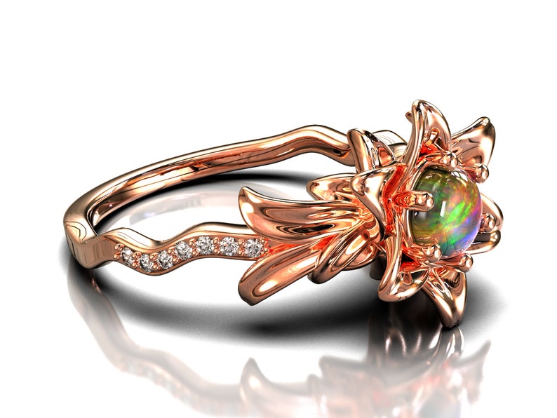 Puede incluir: Anillo de oro rosa con dise&ntilde;o floral y una piedra preciosa de &oacute;palo en el centro. La banda del anillo tiene un patr&oacute;n ondulado con peque&ntilde;as piedras preciosas transparentes. El &oacute;palo muestra colores verdes, azules y morados.
