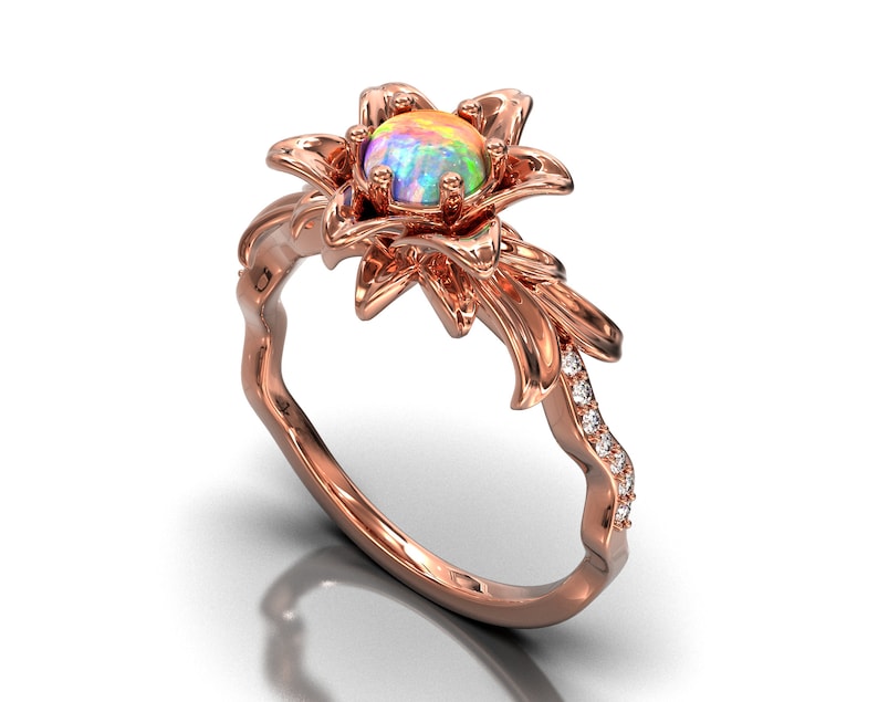 Puede incluir: Anillo de oro rosa con dise&ntilde;o floral y &oacute;palo en el centro. El anillo tiene un engaste floral y una banda adornada con peque&ntilde;os diamantes brillantes. El &oacute;palo muestra una gama de colores.