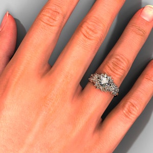 May include: A silver ring with a large, round, clear gemstone surrounded by smaller gemstones. The ring is on a person's finger.