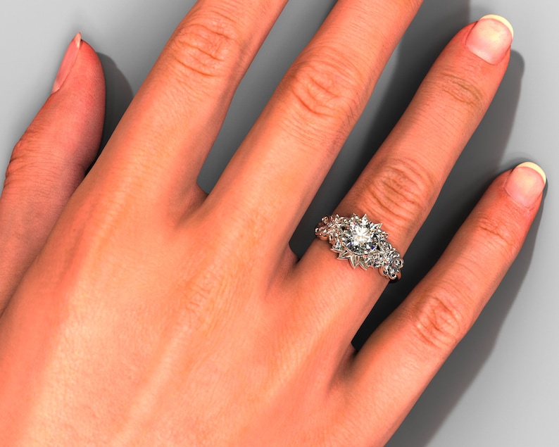May include: A silver ring with a large, round, clear gemstone surrounded by smaller gemstones. The ring is on a person's finger.