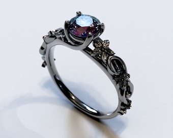 May include: A black metal ring with a large, iridescent gemstone set in a floral design. The ring features delicate, intricate details and a unique, nature-inspired style.