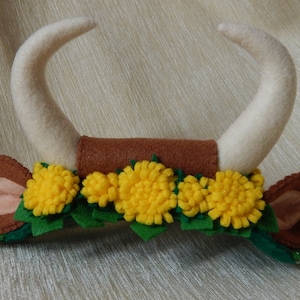 May include: A brown felt headband with two white felt horns, a brown felt band, and a row of yellow felt flowers with green felt leaves.