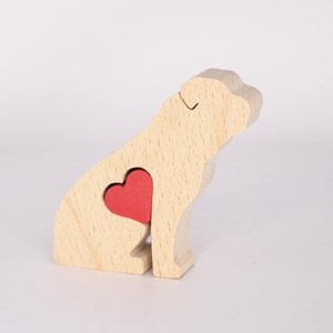 Puede incluir: Figurita de perro de madera con un coraz&oacute;n rojo recortado en el &aacute;rea del pecho. La figurita est&aacute; hecha de madera clara y tiene un dise&ntilde;o simple.