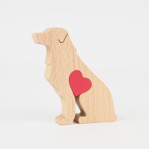 May include: Wooden dog figurine with a red heart-shaped insert. The dog is light brown with a black line for the eye and a red heart. The figurine is sitting down.