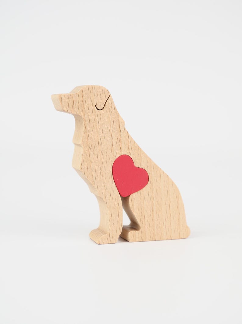 May include: Wooden dog figurine with a red heart-shaped insert. The dog is light brown with a black line for the eye and a red heart. The figurine is sitting down.