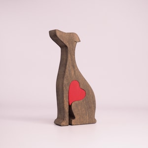 May include: Wooden figurine of a dog sitting with a red heart cutout in its chest.