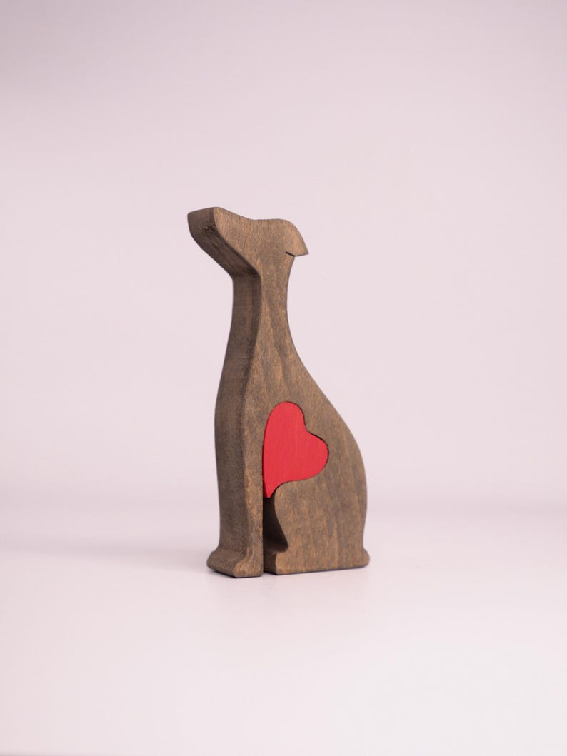 May include: Wooden figurine of a dog sitting with a red heart cutout in its chest.