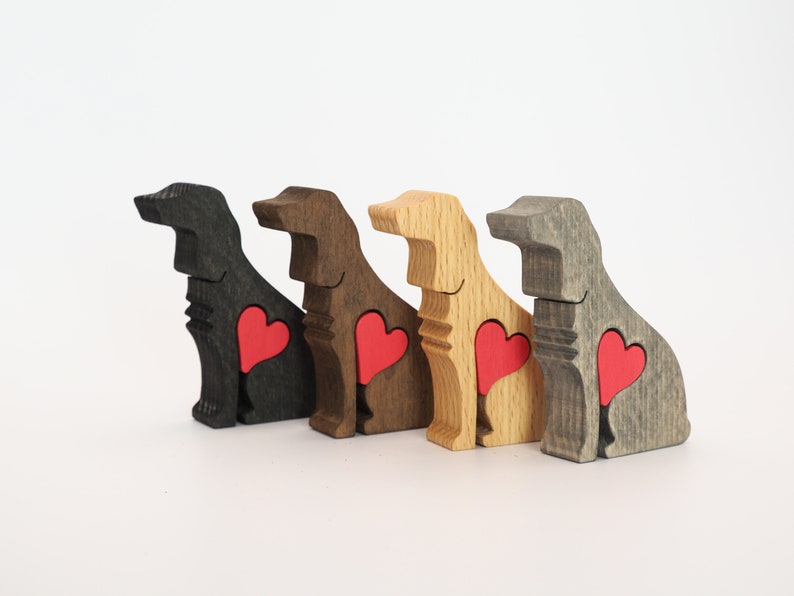 May include: Four wooden dog figurines, each painted a different color: black, brown, natural wood, and gray. Each dog has a red heart cutout on its chest.