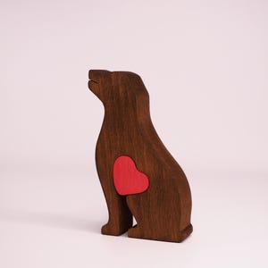 May include: A wooden dog figurine with a red heart cutout on its chest. The dog is sitting with its head tilted up.