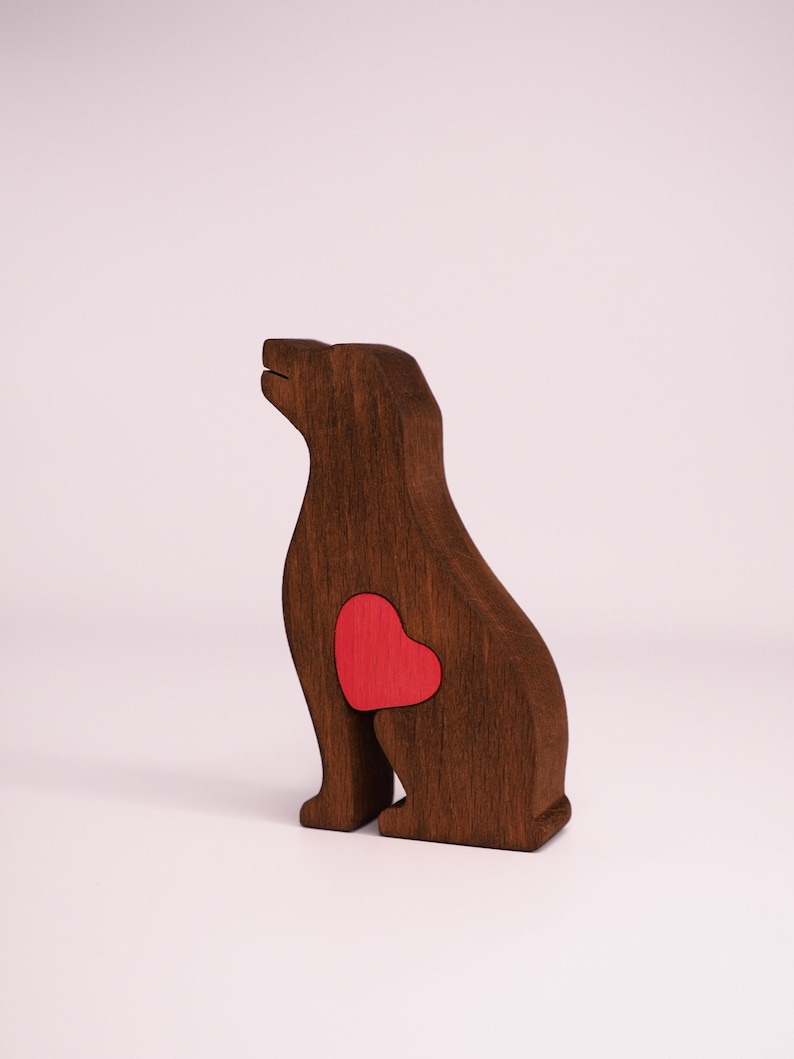 May include: A wooden dog figurine with a red heart cutout on its chest. The dog is sitting with its head tilted up.