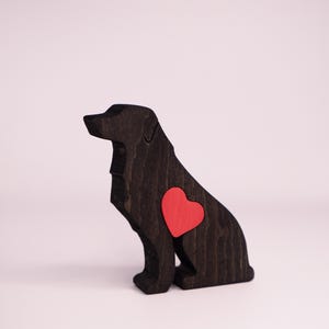 May include: A wooden dog figurine in a sitting position, stained dark brown. A bright red heart is inlaid on the dog's side. The figurine is a decorative item, likely for home decor or as a gift for dog lovers.