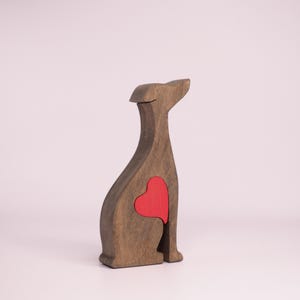 May include: Wooden figurine of a dog sitting with a red heart cutout in its chest.