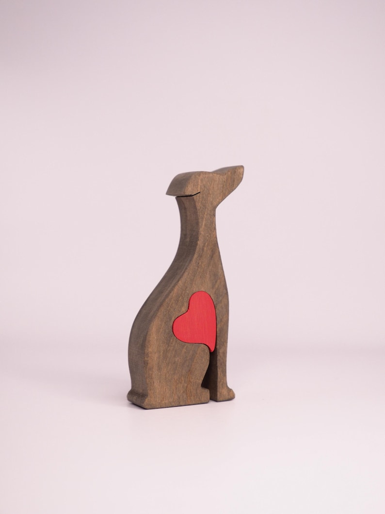 May include: Wooden figurine of a dog sitting with a red heart cutout in its chest.