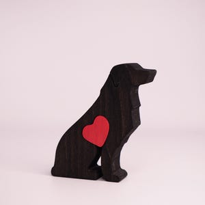 May include: A black wooden dog figurine with a red heart-shaped accent on its side. The dog is in a sitting position, with a smooth, polished finish. The background is a plain white.