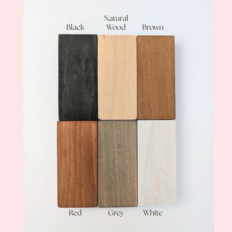 May include: A color palette of six rectangular wooden blocks, each displaying a different stain. The colors include black, natural wood, brown, red, grey, and white. The names of the colors are labeled above or below each block.