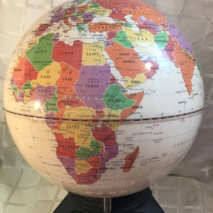 May include: A colorful, educational GeoSafari Explorer Toy globe with country names and borders. The globe sits on a black and white base with buttons labeled "Stop", "Repeat", "Help", and numbers 1-4. The text "EXPLORATOY" is visible.
