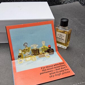 May include: A perfume bottle with a black cap sits next to a pop-up card featuring various perfume bottles. The card has text that reads, "For those who love the most luxurious perfumes&mdash;but don't wish to pay the sky-high prices."
