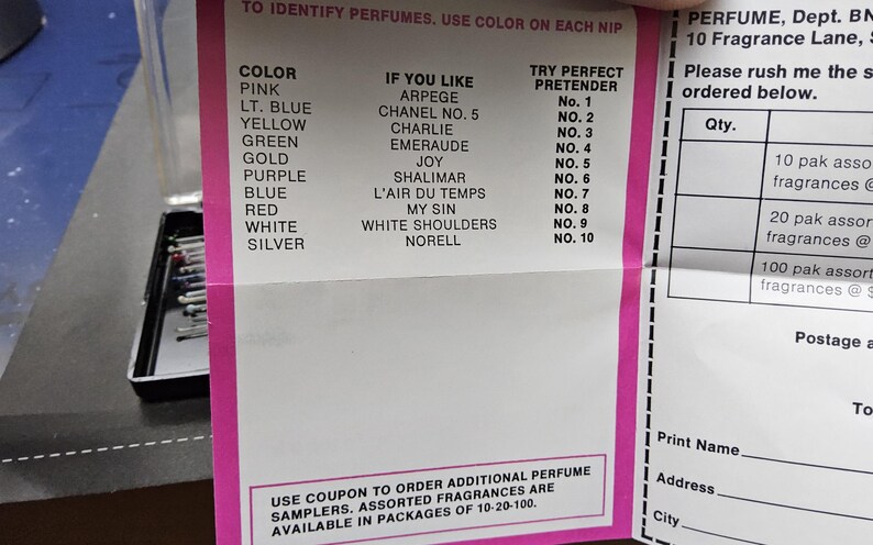 May include: A printed sheet with perfume identification information. The sheet lists perfume colors, corresponding fragrances, and "Try Perfect Pretender" numbers. A black case with perfume samples is visible on the left. The sheet also includes an order form.