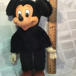 Puede incluir: Un mu&ntilde;eco de peluche vintage de Mickey Mouse. El mu&ntilde;eco tiene un cuerpo negro, orejas grandes negras y una cara bronceada con una expresi&oacute;n sonriente. Tiene zapatos rojos y mide aproximadamente 46 cm de alto.