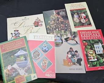 May include: A selection of vintage Hallmark Keepsake ornament books and catalogues. Titles include "Keepsake Magic Keepsake Ornaments", "Keepsake Ornament Collection", and "1991 Dream Book". The books feature colourful illustrations of Christmas ornaments.