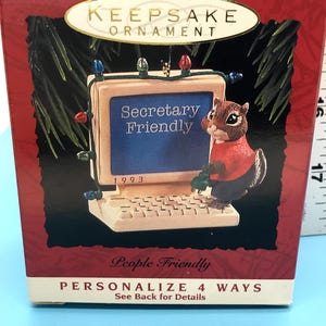 May include: A Keepsake ornament box with a computer-themed design. The ornament features a chipmunk wearing a red shirt, holding a green object, and standing next to a computer screen that reads "Secretary Friendly" with the year 1993.