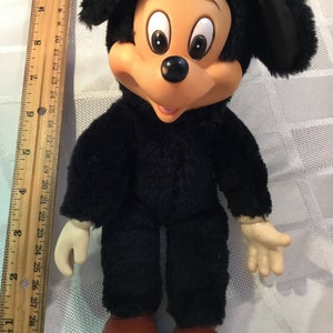 Puede incluir: Mu&ntilde;eco de peluche vintage de Mickey Mouse. El mu&ntilde;eco tiene un cuerpo negro y peludo, pies grandes rojos y una cara bronceada con ojos grandes. El mu&ntilde;eco mide aproximadamente 28 cm de alto.