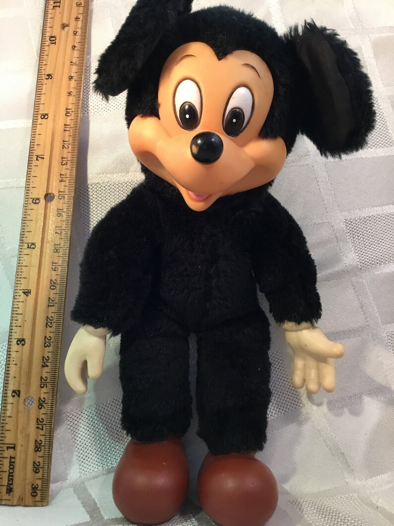 Puede incluir: Mu&ntilde;eco de peluche vintage de Mickey Mouse. El mu&ntilde;eco tiene un cuerpo negro y peludo, pies grandes rojos y una cara bronceada con ojos grandes. El mu&ntilde;eco mide aproximadamente 28 cm de alto.