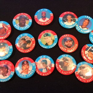 May include: A collection of vintage baseball player pins. Each circular pin features a player's portrait, name, and team logo, with a red and blue color scheme. The pins are from the early 1990s.