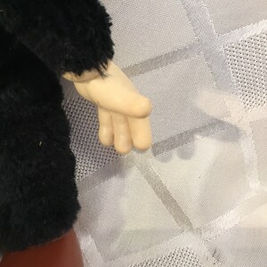 Puede incluir: Primer plano del brazo y la mano de una mu&ntilde;eca. El brazo de la mu&ntilde;eca est&aacute; cubierto de material negro y difuso, y la mano es de un tono de piel p&aacute;lido. El brazo de la mu&ntilde;eca est&aacute; doblado por el codo y la mano est&aacute; abierta.