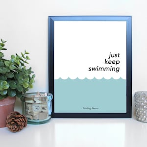 May include: A black framed print with a white background and blue waves at the bottom. The text "just keep swimming" is in black text. The text "Finding Nemo" is in smaller black text at the bottom.