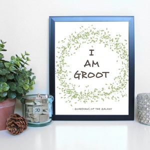 May include: A framed print with a white background and a green leaf design. The text "I AM GROOT - GUARDIANS OF THE GALAXY" is printed in brown.