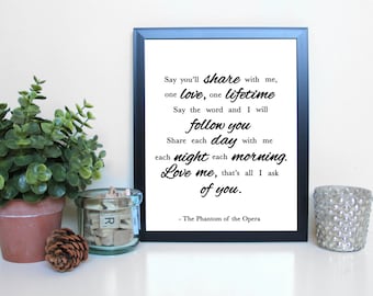 May include: A black framed print with white text on a white background. The text reads: "Say you'll share with me, one love, one lifetime. Say the word and I will follow you. Share each day with me, each night each morning. Love me, that's all I ask of you. - The Phantom of the Opera".