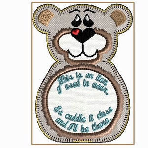 May include: A gray embroidered teddy bear with a brown stitched outline. The bear has a white face with black eyes, a red heart nose, and a brown stitched mouth. The bear is holding a white circle with brown stitching and the text "This is an item I used to wear, So cuddle it close and I'll be there." in blue text.