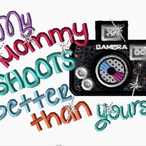 May include: A colorful embroidered design with the text "My Mommy Shoots Better Than Yours" and a black and silver camera with glitter accents.