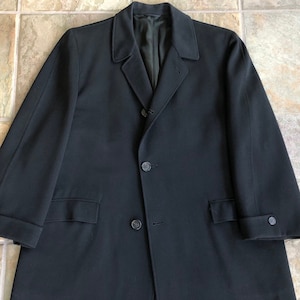 May include: A black long-sleeved coat with a single-breasted closure and two front pockets.